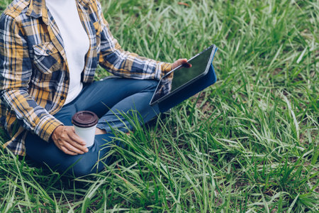 Asian woman sitting and drinking coffee in the gardenの写真素材