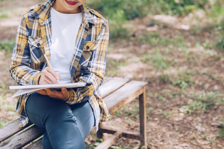 Asian woman sitting and writing in the gardenの写真素材