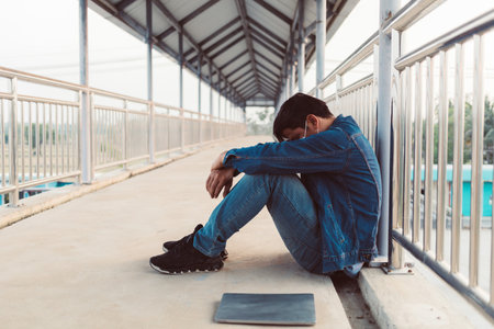 Stressed Asian man sitting on a footbridgeの写真素材