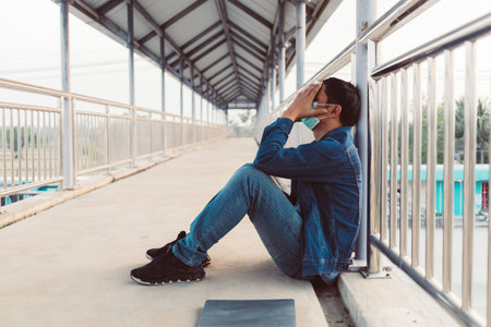 Stressed Asian man sitting on a footbridgeの写真素材