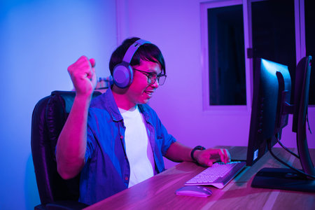 Asian man playing games at home at nightの写真素材