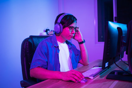 Asian man playing games at home at nightの写真素材