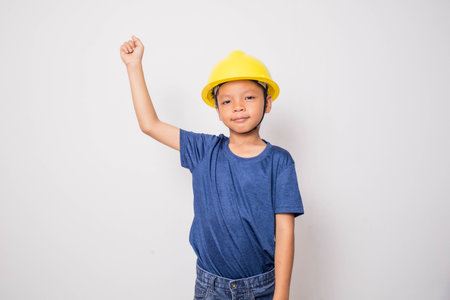 Little asian boy wearing a yellow hard hat on white background.の写真素材
