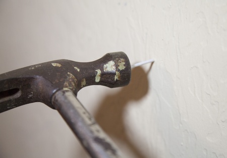 Hammer striking nail on wall with hammer shadowの写真素材