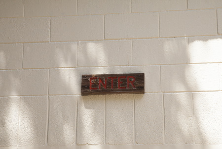 Small wooden enter sign on brick background