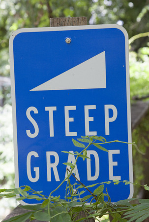 Blue steep grade sign with white lettersの写真素材