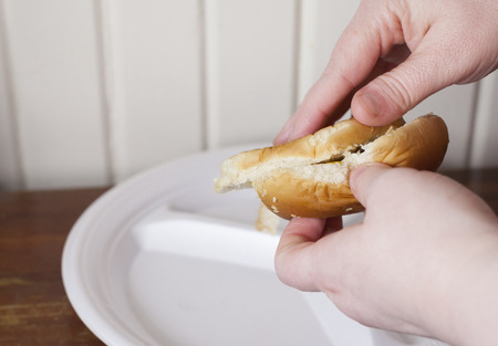 Someone preparing hamburger buns by spreading condiments on themの写真素材
