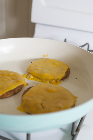 Three veggie cheeseburgers frying on the stove topの写真素材
