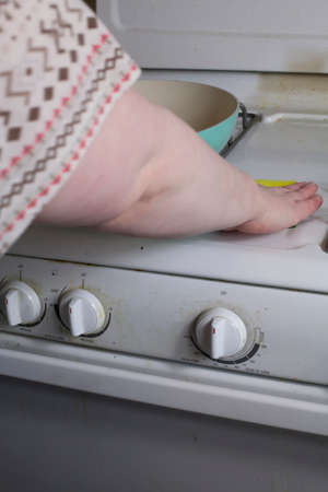 Woman scrubbing a stove with a cleaning spongeの写真素材