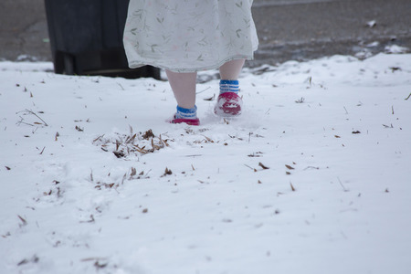 Woman walking toward a garbage can in the snowの写真素材