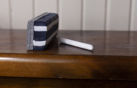 Eraser and a single piece of chalk on a tableの写真素材