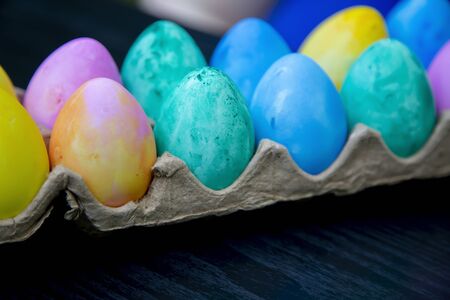 A dozen plastic Easter eggs dyed yellow, pink, green, blue and purpleの写真素材