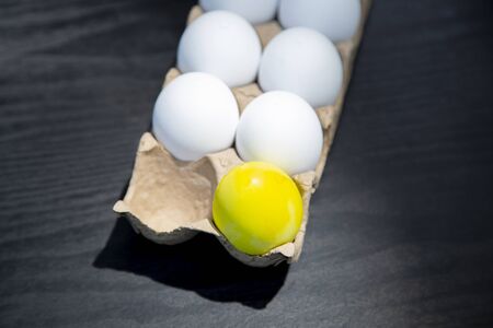 A carton of plastic Easter eggs with one egg missing and one colored yellowの写真素材