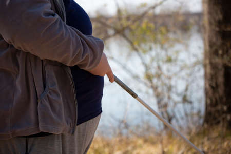 Close up of a hand holding a white cane with a waterway in the backgroundの写真素材