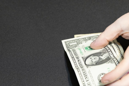 LOUISIANA/USA  â OCTOBER 16 2021: Hand holding a one dollar bill on a black backgroundのeditorial素材