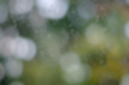 Blurred water drops on window glass with circular bokeh background, designed for adding text overlays and any creative ideas.の写真素材