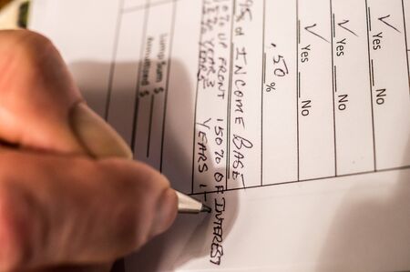 Close up shot of someone working on tax formsの写真素材