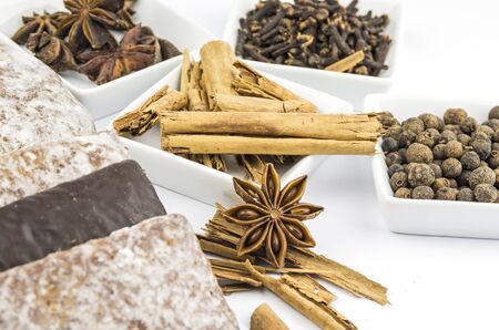 Some gingerbread cookies and several spices on white