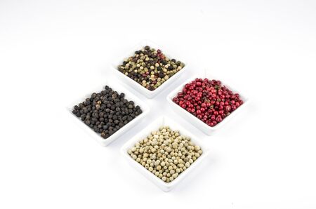 Red, white, black and sorted peppercorns on white