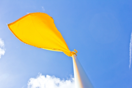 yellow flag at field on blue sky backgroundの写真素材