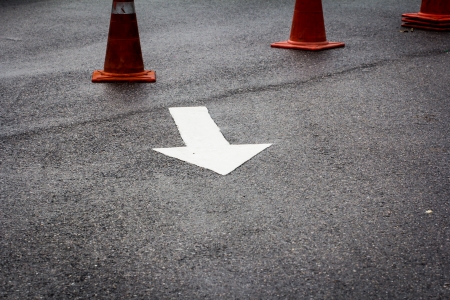 A white traffic arrow signage on an asphalt roadの写真素材