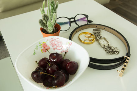 Cherries in bowl on table with fashionable female accessoriesの写真素材