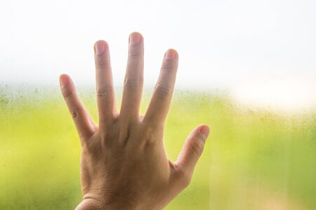 hand on window glass with water dropsの写真素材
