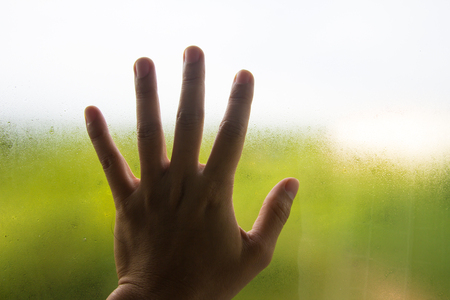 hand on window glass with water dropsの写真素材