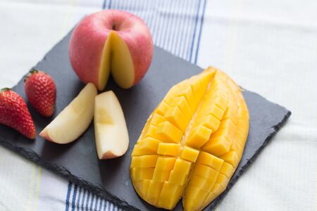 Mango and apple on a black stone plateの写真素材