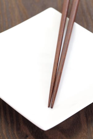 Asian table white plate and brown wood chopstickの写真素材
