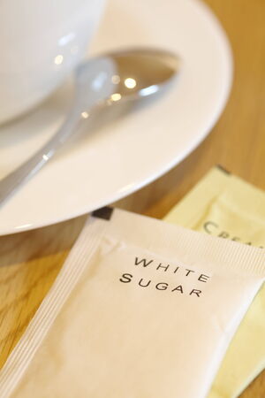 White sugar paper pack beside a cup of coffeeの写真素材