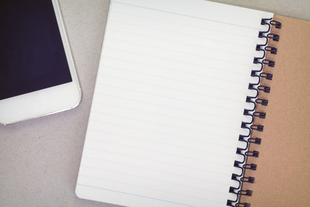 Blank notebook and mobile phone on wooden table