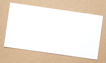 Blank white paper note on brown paper backgroundの写真素材