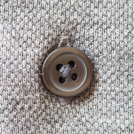 Close - up brown plastic button on grey shirt