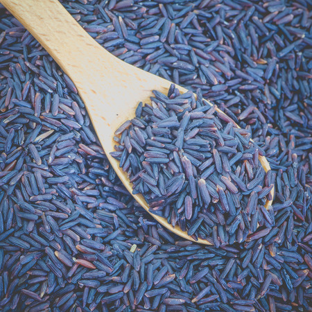 Healthy uncooked brown rice in wooden spoonの写真素材