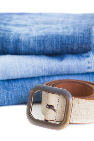 Leather belt and blue denim jean isolated on white backgroundの写真素材