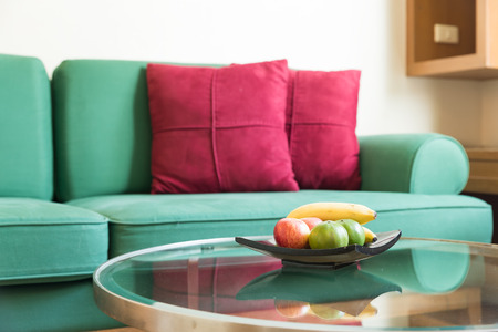 Fresh fruit and green sofa with red backrest pillow in living roomの写真素材