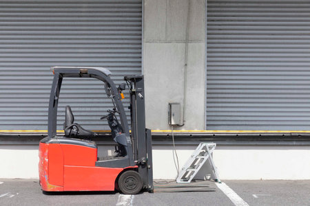 A forklift is parked in front of a warehouse in the industrial area