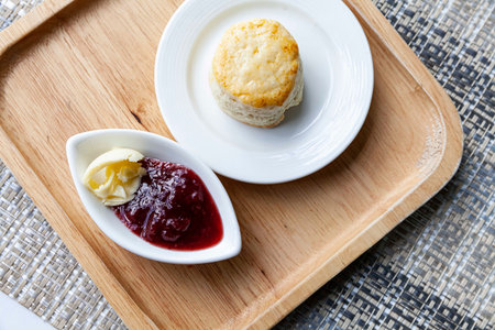 Scones and strawberry jam cups on wooden trays on tables at the cafÃ©