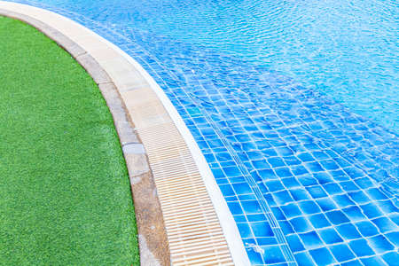 Wide swimming pool and green artificial turf inside the villaの写真素材