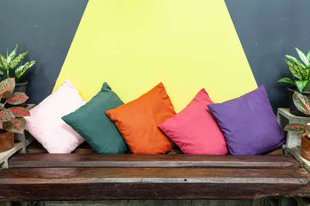 An old wooden sofa and multicolored fabric cushions in the living room of the houseの写真素材