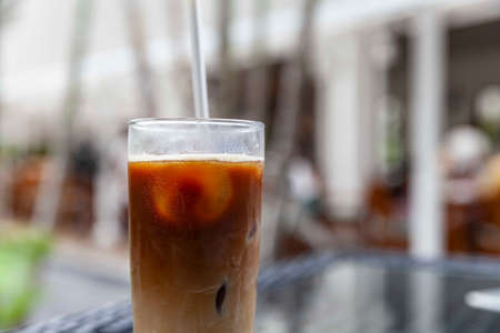 Iced cappuccino in a glass with straws on a table at a trendy cafeの写真素材