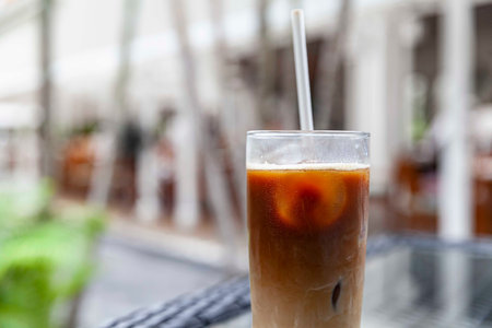 Iced cappuccino in a glass with straws on a table at a trendy cafe