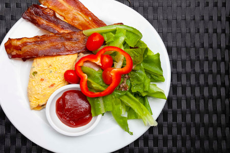 Western breakfast, scrambled eggs, bacon and fresh vegetables with tomato sauce