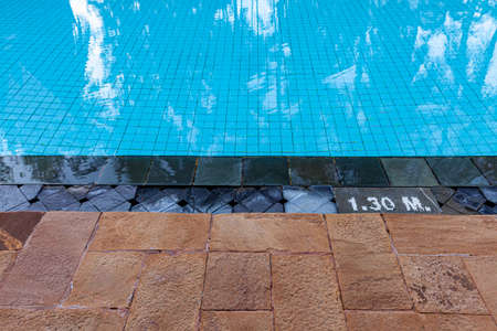 Wide swimming pool and brown stone floor inside the villaの写真素材