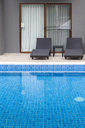 Wide swimming pool and brown stone floor inside the villa