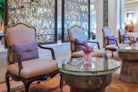 Purple plastic flowers in a glass vase decorate the living room of a luxury homeの写真素材