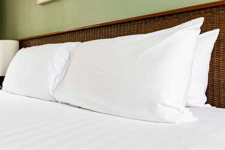 Clean white pillows at the head of the bed in the bedroomの写真素材