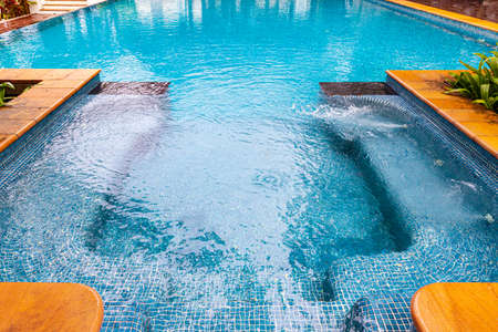 Wide swimming pool and brown stone floor inside the villaの写真素材