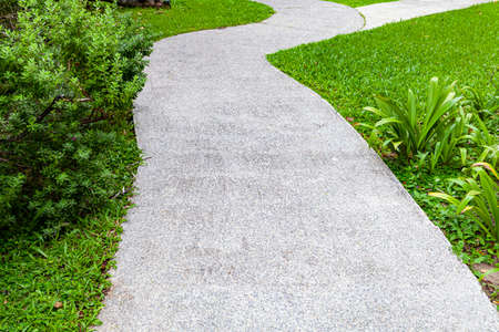 Long concrete walkway in the summer green gardenの写真素材
